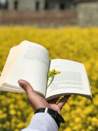 Midsection of man holding book against blurred background