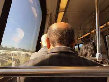 Rear view of people sitting in train during sunny day