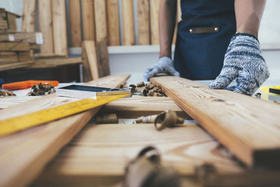 Midsection of carpenter holding plank on table