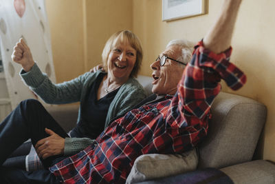 Senior couple sitting on sofa and singing