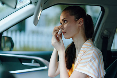 Young woman talking on mobile phone while sitting in car