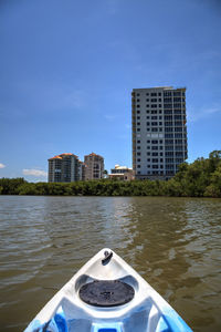 Buildings by river against blue sky