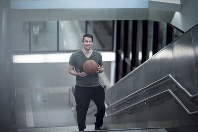 High angle portrait of young man with basketball moving up on steps