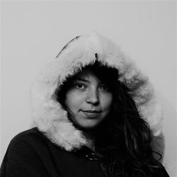 Close-up portrait of young woman wearing warm clothing by wall