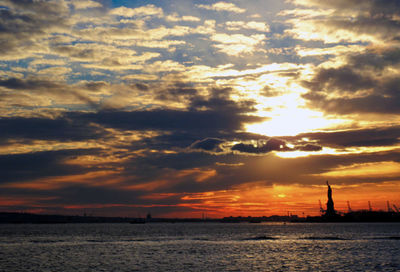 Scenic view of sea against dramatic sky during sunset
