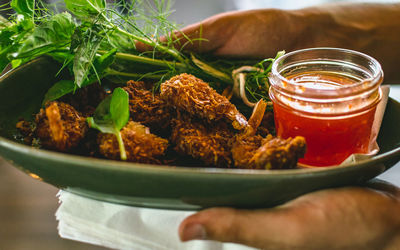 Cropped image of hand holding food in plate