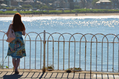 Rear view of woman standing by sea against sky