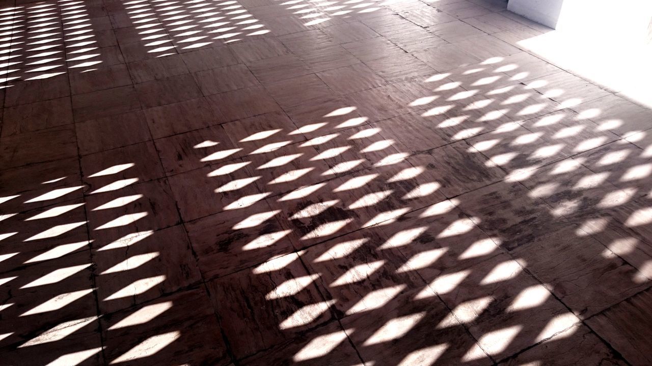 HIGH ANGLE VIEW OF SUNLIGHT FALLING ON TILED FLOOR IN CITY