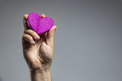 Midsection of person holding heart shape against black background