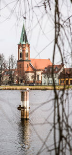 Church by building against sky in city during winter