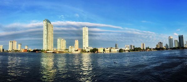 City at waterfront against cloudy sky