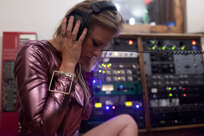 Young woman listening to music through large headphones