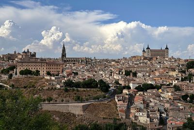 Buildings in town against cloudy sky