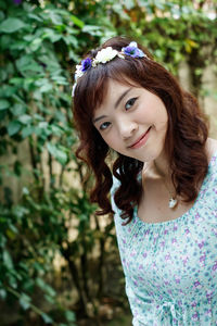 Portrait of beautiful woman wearing flowers against plants