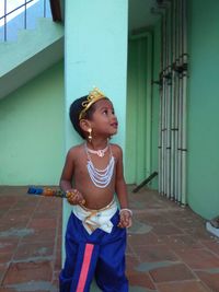 Cute girl looking away while standing against wall