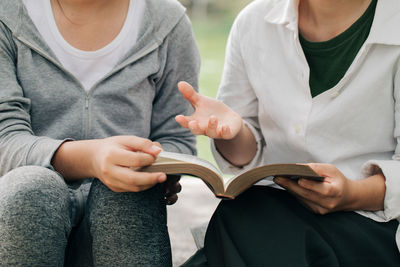 Midsection of couple holding book