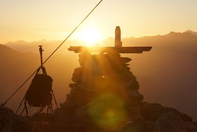 Silhouette sculpture on mountain against sky during sunset