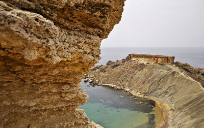 Rock formations on sea shore against sky