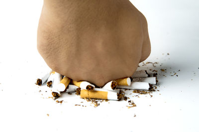 Close-up of broken cigarette on floor against white background