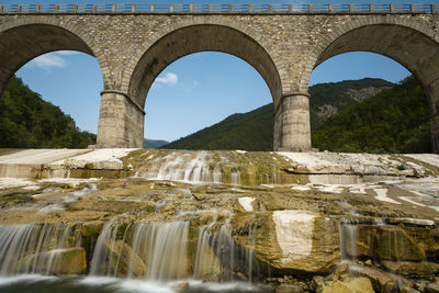 Arch bridge over river against sky