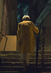 Rear view of man walking on staircase in building