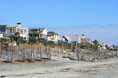 Houses on beach by buildings against blue sky