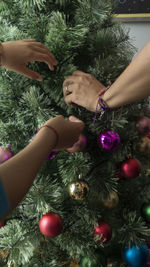 Cropped hand of woman decorating christmas tree