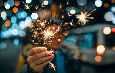 Midsection of person holding sparkler at night