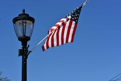 Low angle view of flags against clear blue sky