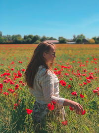 Woman standing by flowering plants on field