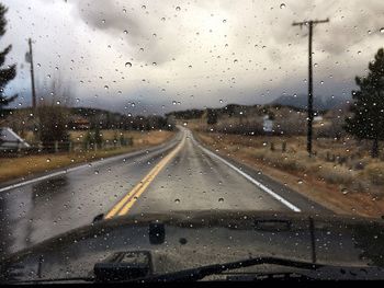 Road seen through wet glass window