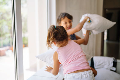 Brother and sister playing at home pillow fight