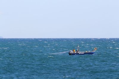 Boat sailing in sea against clear sky