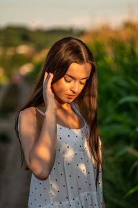 Young woman looking away while standing outdoors