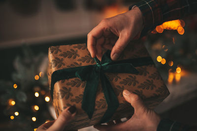 Cropped hand of man and woman opening christmas gift