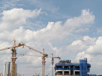 Cranes at construction site against sky