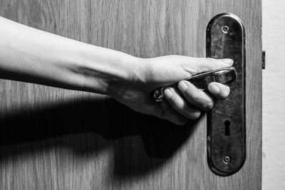 Close-up of human hand on wooden door