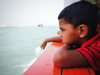 Side view of boy looking at sea from boat