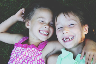 Close up portrait of two cute smiling little girls laying on the grass
