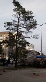 People on street by buildings in city against sky