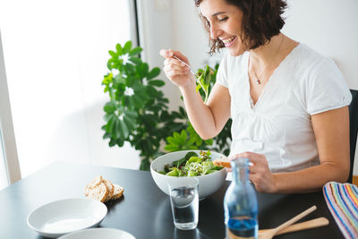 Midsection of woman holding food while sitting on table