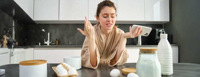 Portrait of young woman preparing food in kitchen