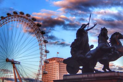 Low angle view of ferris wheel against cloudy sky