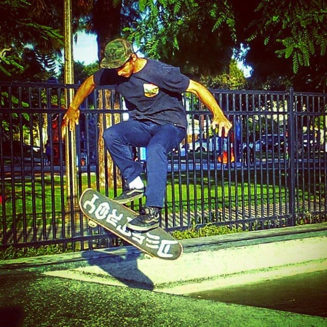 lifestyles, full length, leisure activity, sport, childhood, playground, tree, playing, park - man made space, men, casual clothing, fence, green color, boys, standing, railing, outdoors, protection