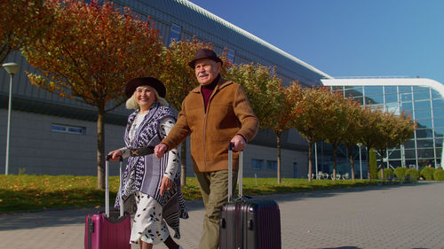 Low angle view of smiling couple walking out from airport