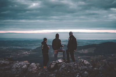 People standing on rock by sea against sky
