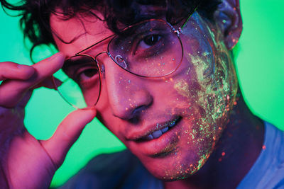 Portrait of man with multi colored face paint wearing eyeglasses