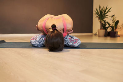 Young woman doing yoga on yoga mat in atmospheric yoga studio