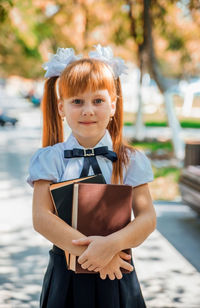 Funny charming little girl with books in her hands, on the first day of school or kindergarten.