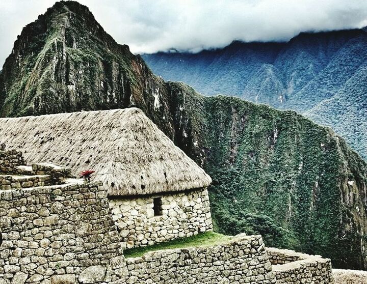 building exterior, sky, built structure, architecture, cloud - sky, stone wall, cloudy, rock - object, stone - object, house, religion, day, spirituality, stone material, mountain, place of worship, cloud, old, roof, outdoors